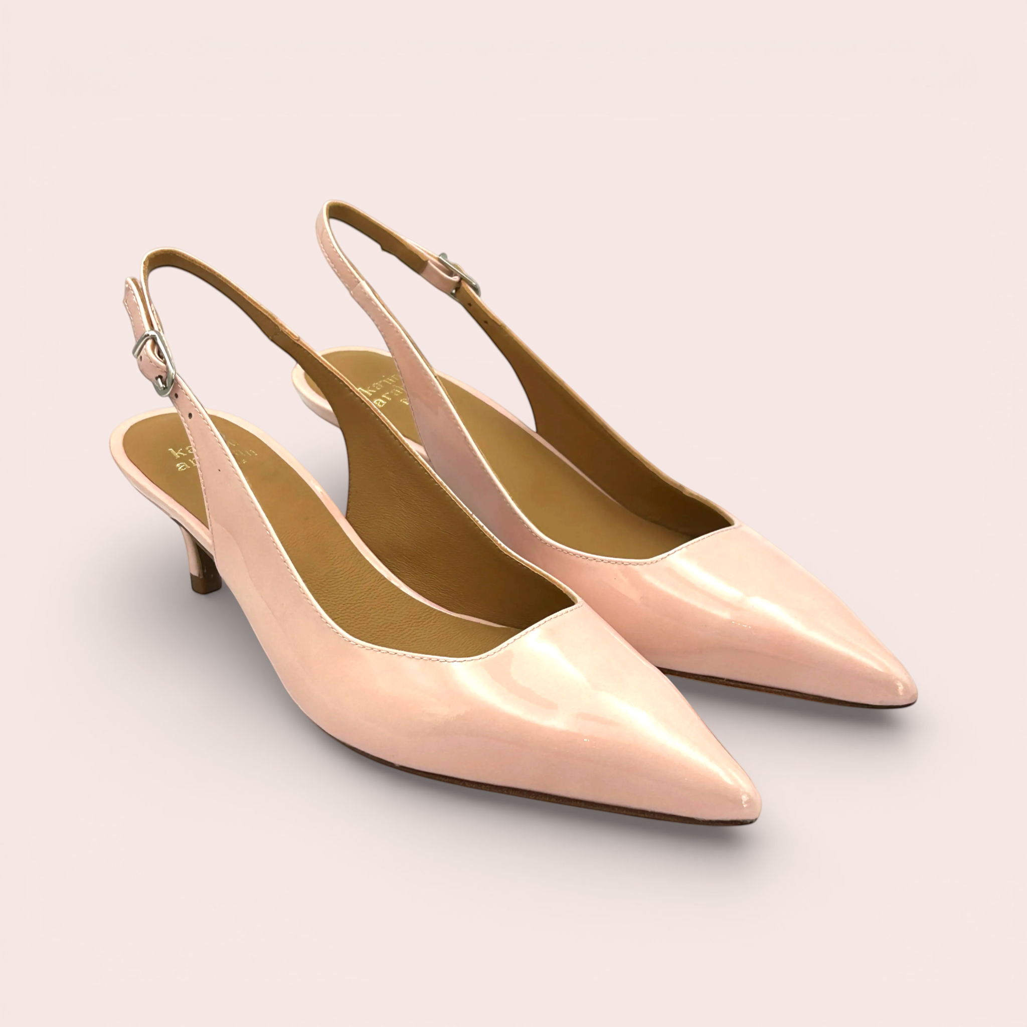 Pale pink patent leather slingback kitten heels with pointed toes and adjustable ankle straps.