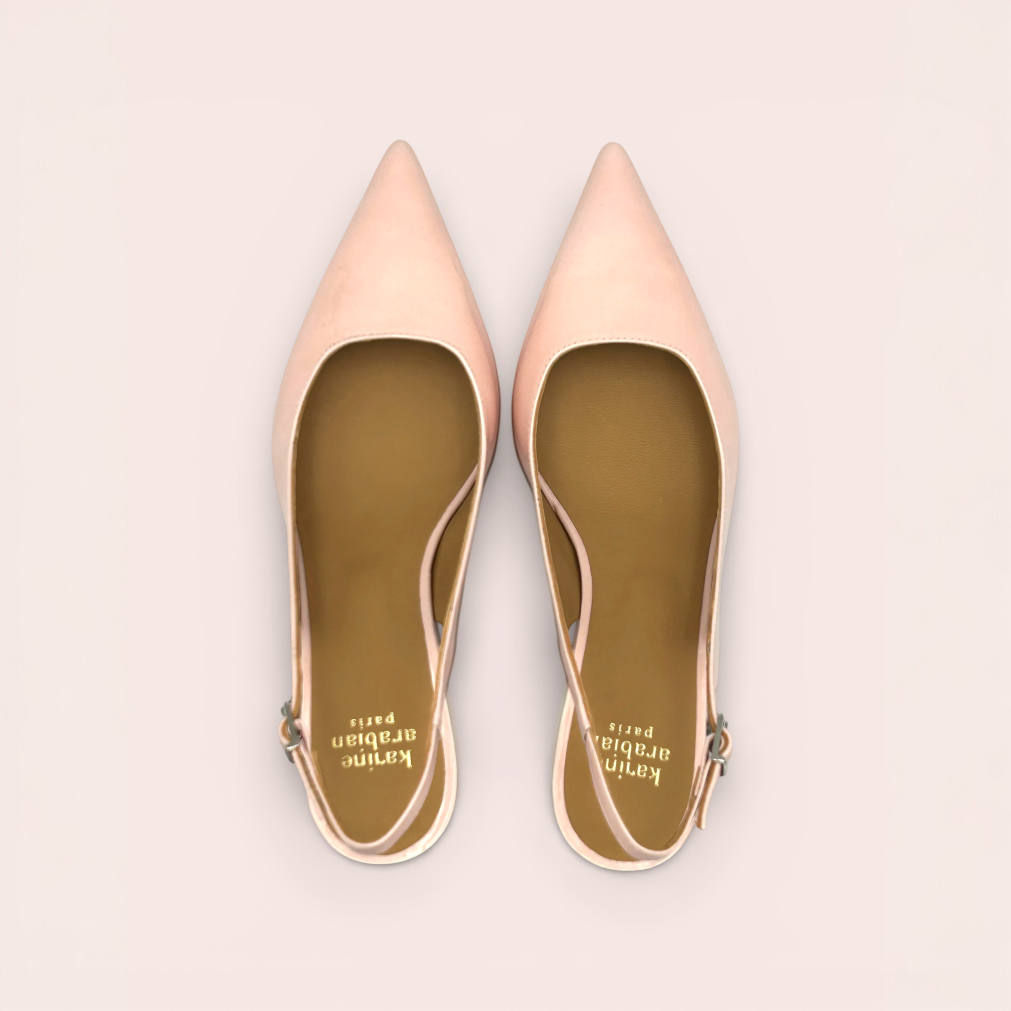 Pale pink patent leather slingback heels with pointed toes and a kitten heel. Features a low-cut vamp and an adjustable ankle strap.