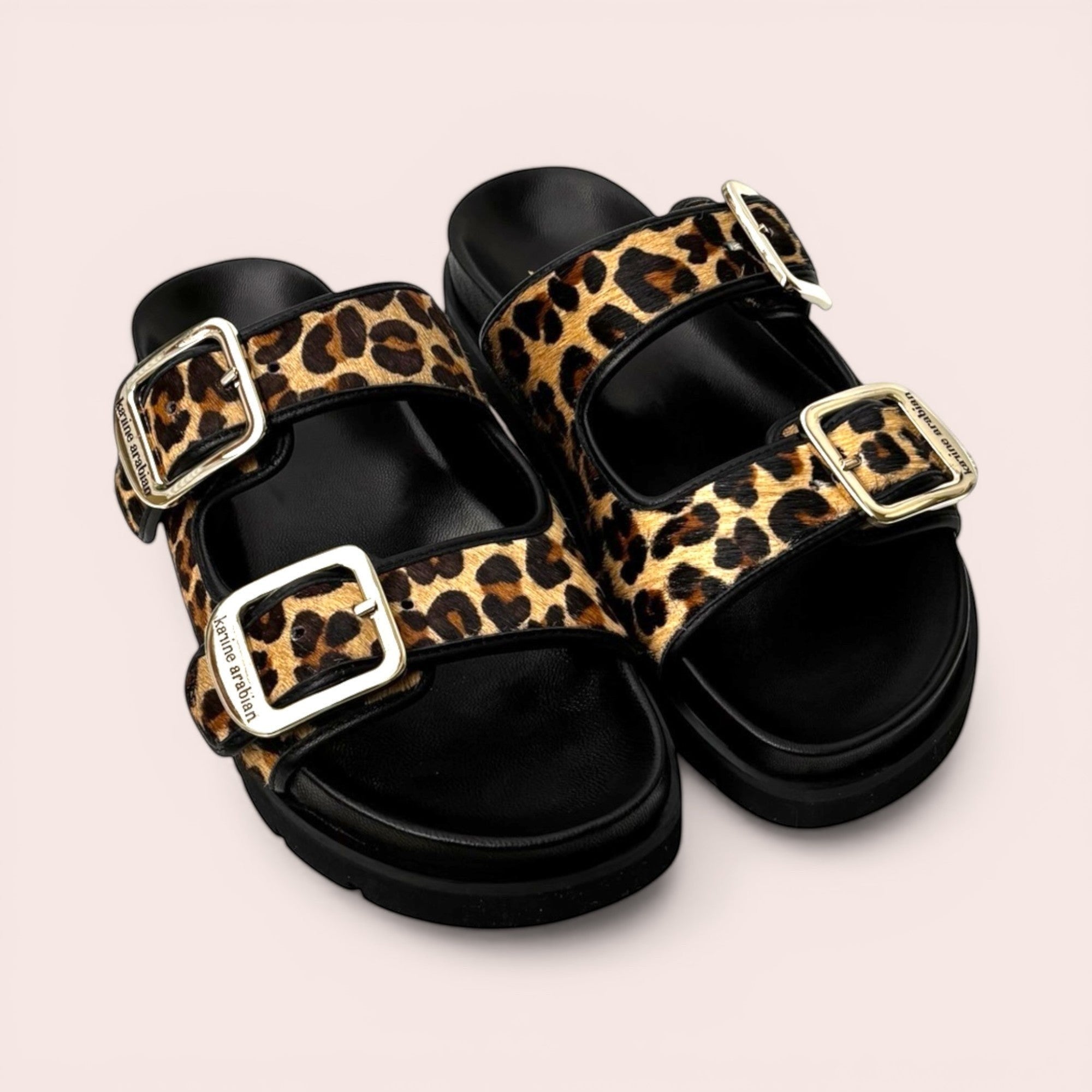 Leopard print platform sandals with black chunky soles and adjustable gold-tone buckles.