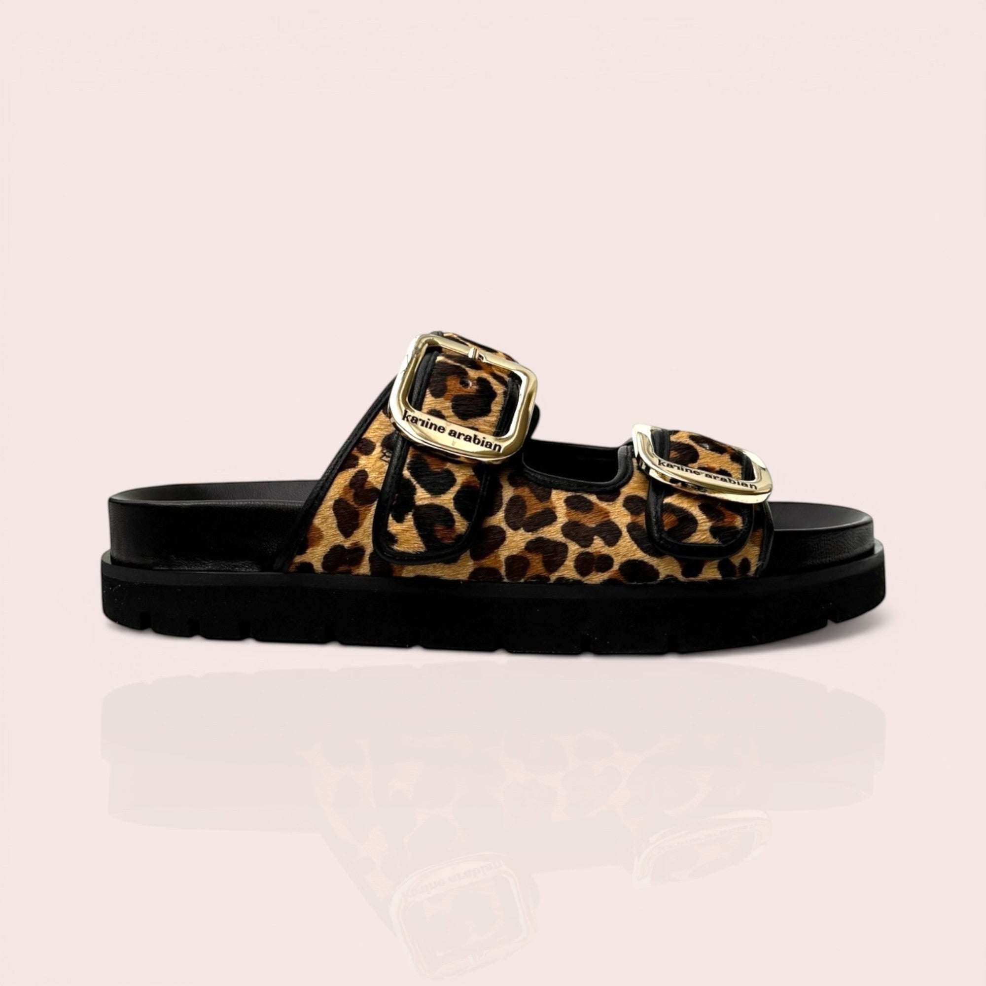 Black platform sandals with leopard print straps and gold-tone buckles. Features a chunky sole and adjustable straps.