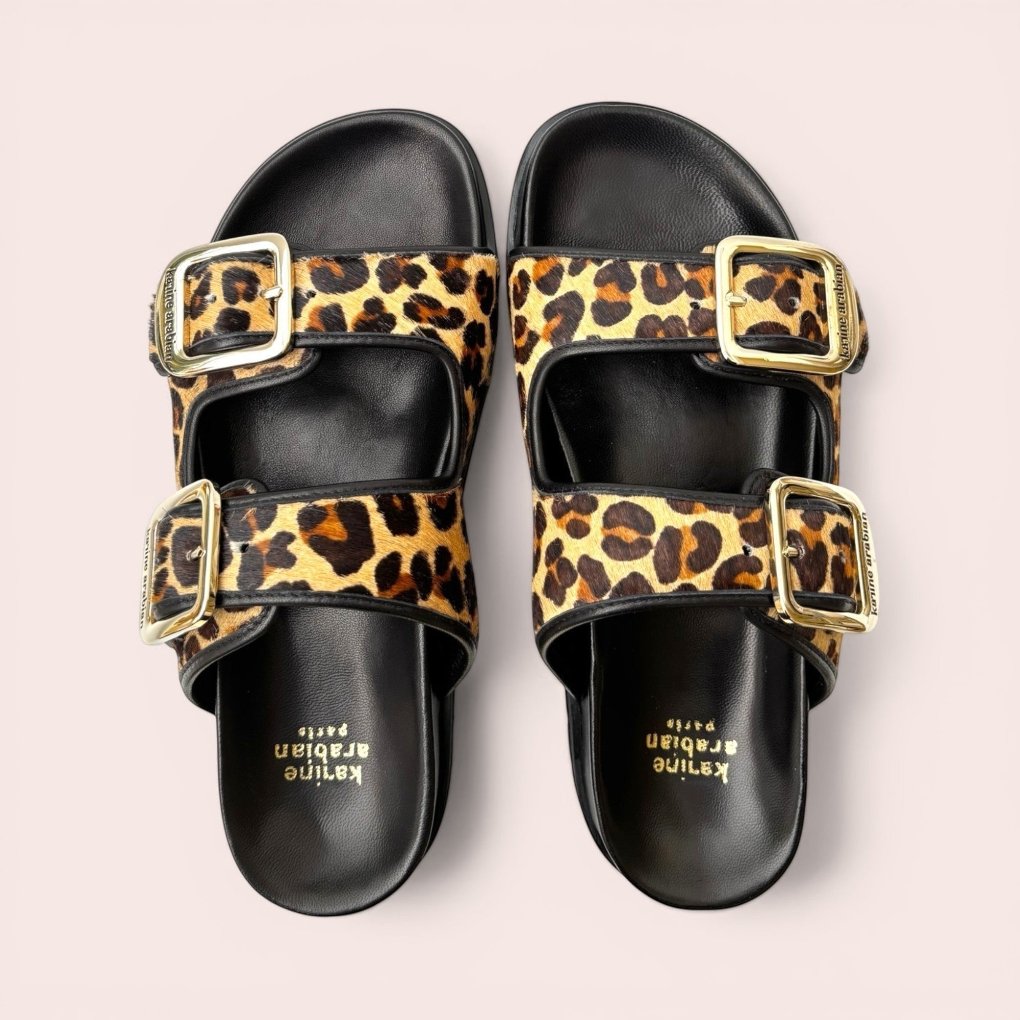 Leopard print platform sandals with black leather trim and gold-tone adjustable buckles on a chunky sole.