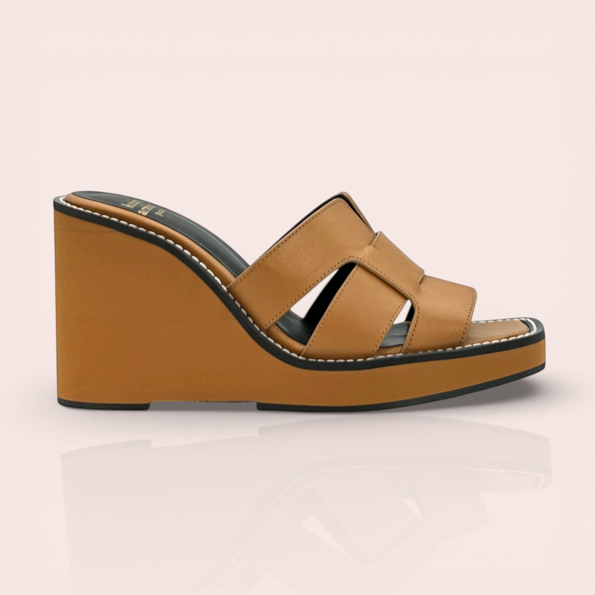 Camel leather mule with interwoven straps and a wedge heel, featuring white stitching and a black sole detail.