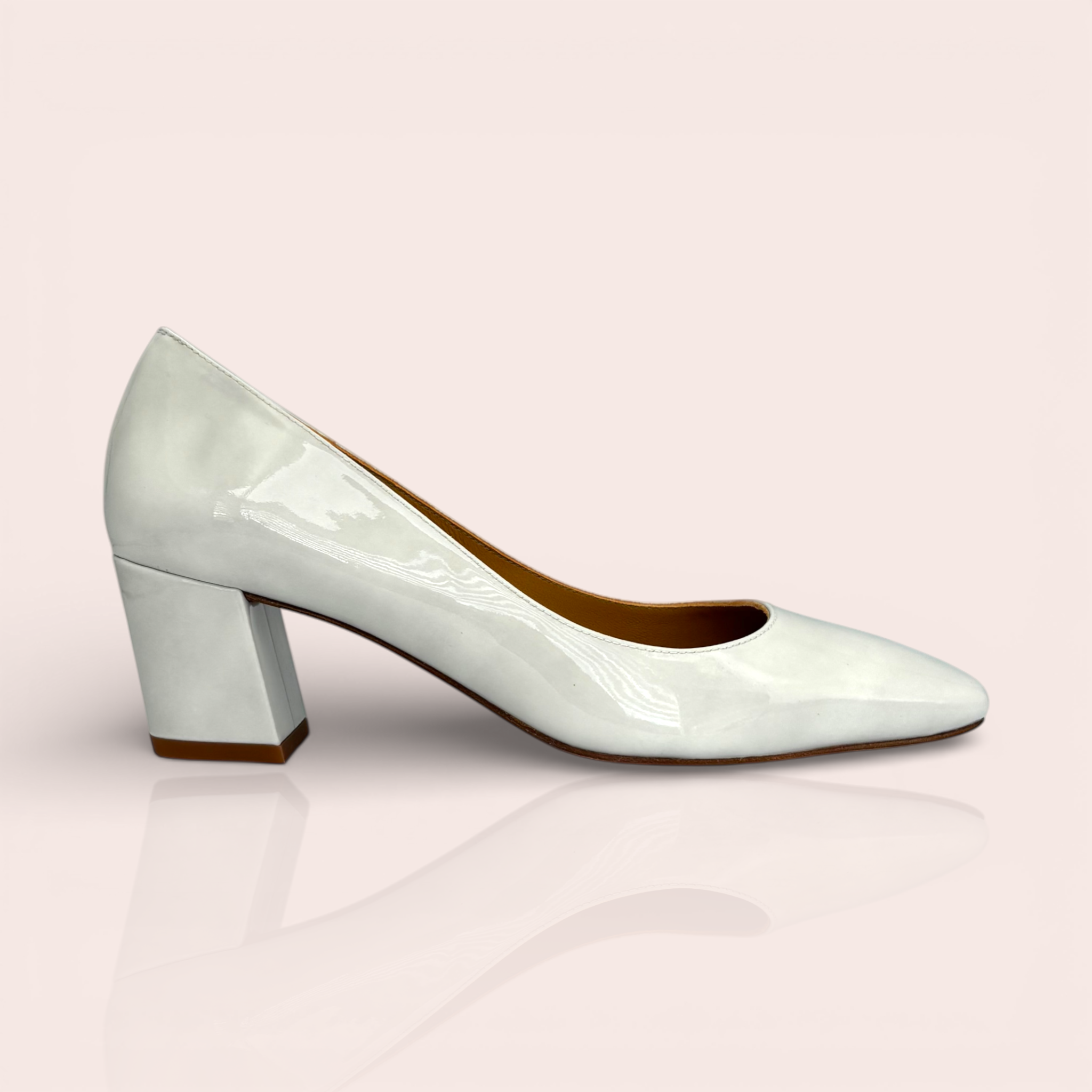White patent leather pump with a square toe and a chunky block heel. The Yolanda shoe features a sleek, modern design.