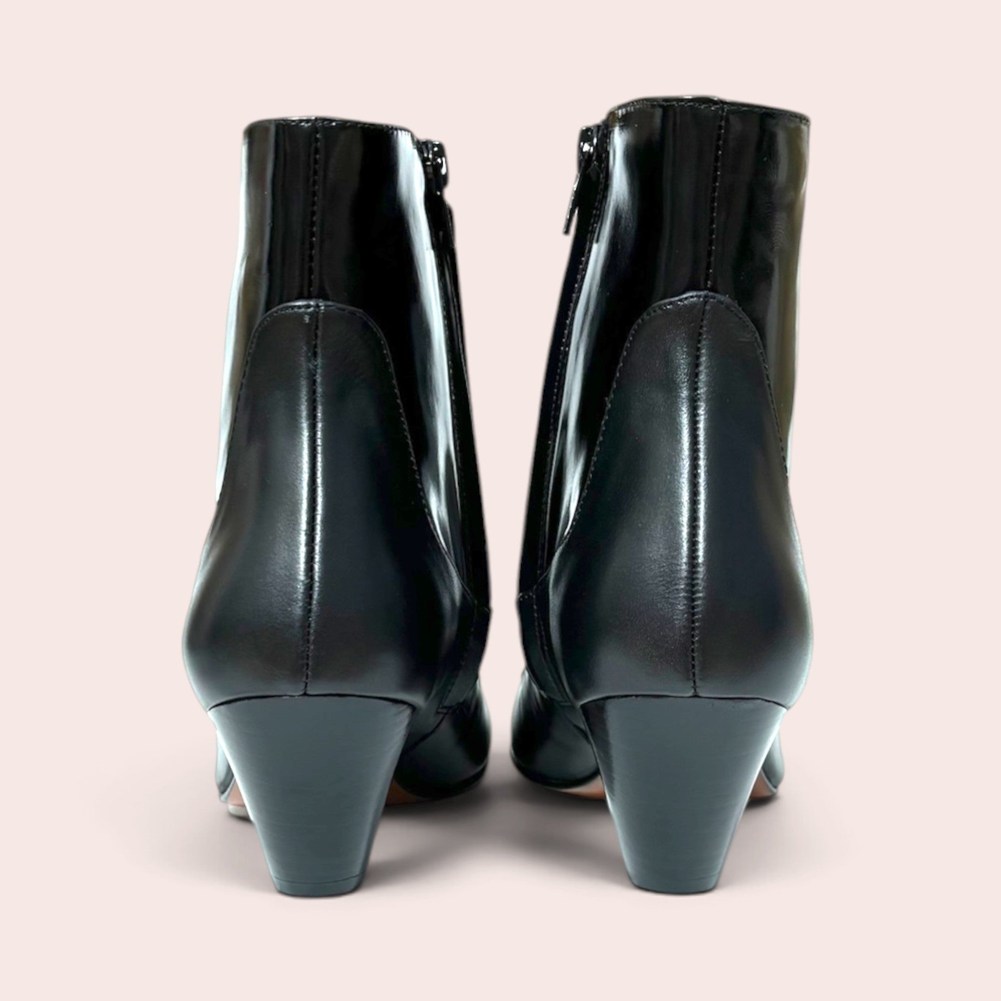 Back view of black high-shine ankle boots with a sculptural mid-height heel and side-zip closure.