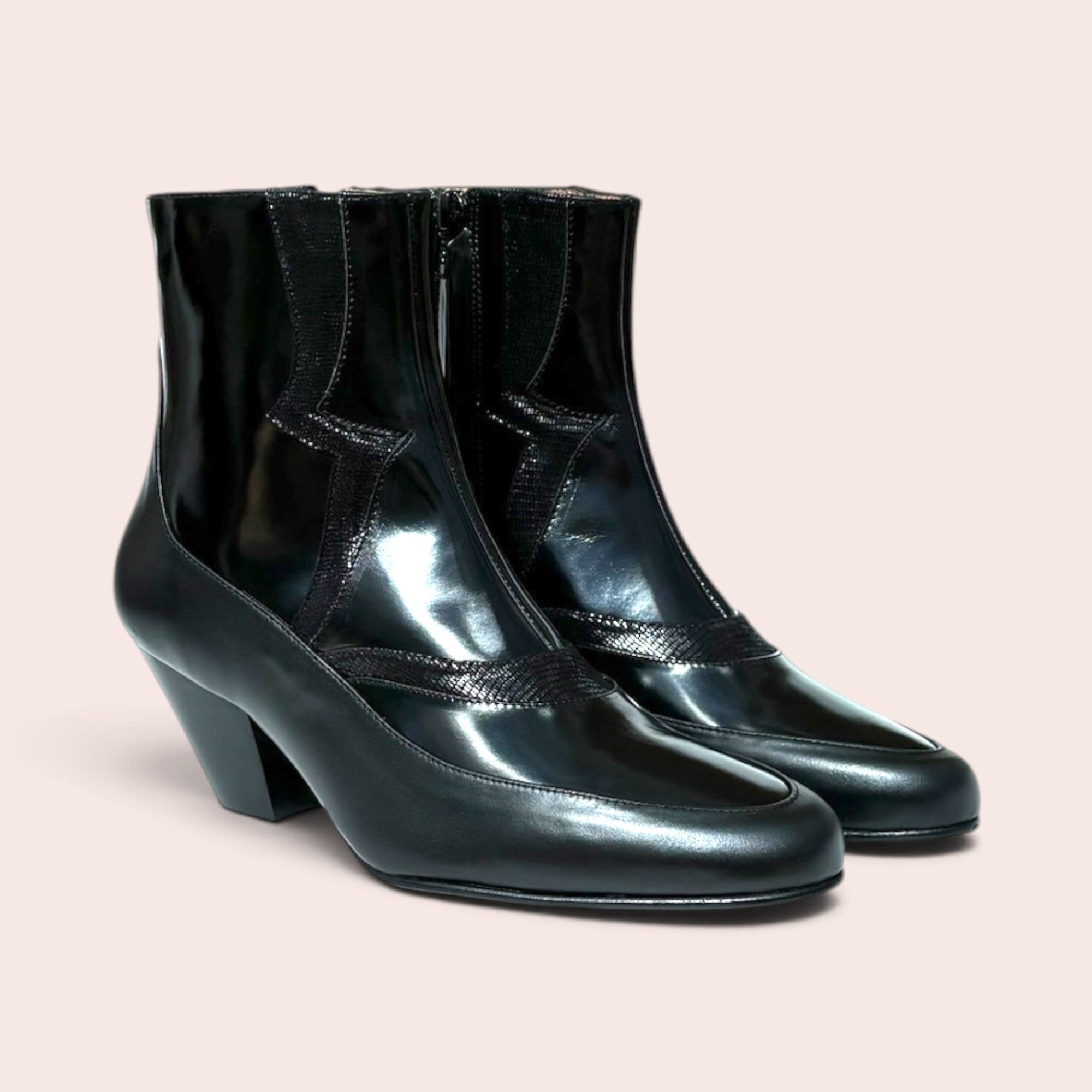 Black high-shine ankle boots with a sculptural heel, pointed toe, and western-inspired textured paneling.