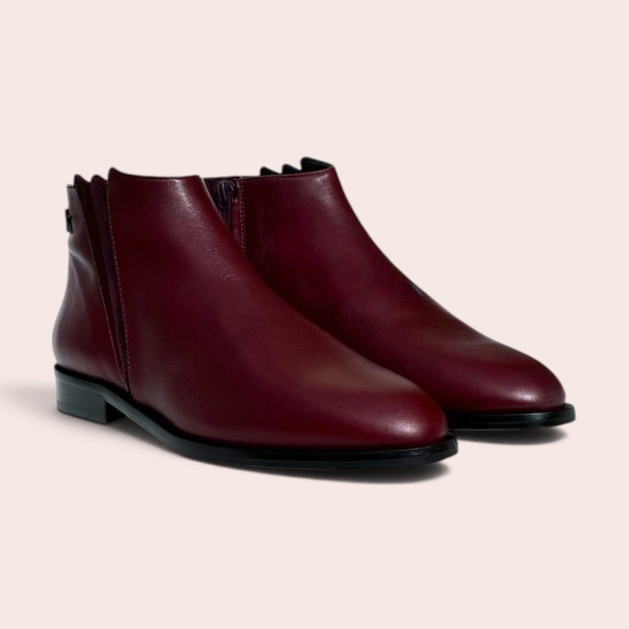 Bottines plates pour femme en cuir bordeaux avec fermeture éclair latérale et talon bas, design épuré et élégant.