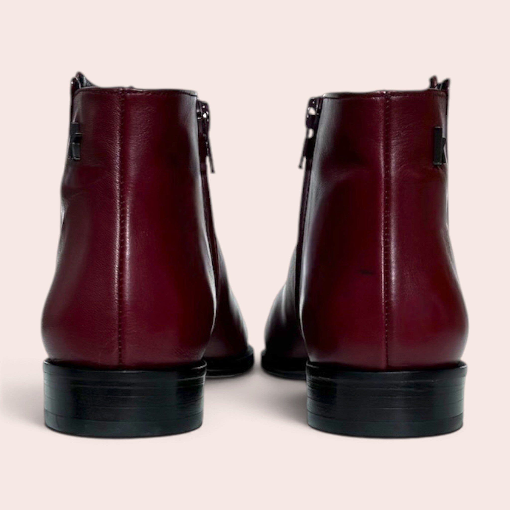 Vue arrière de bottines plates pour femme en cuir bordeaux avec fermeture éclair latérale et talon bas noir
