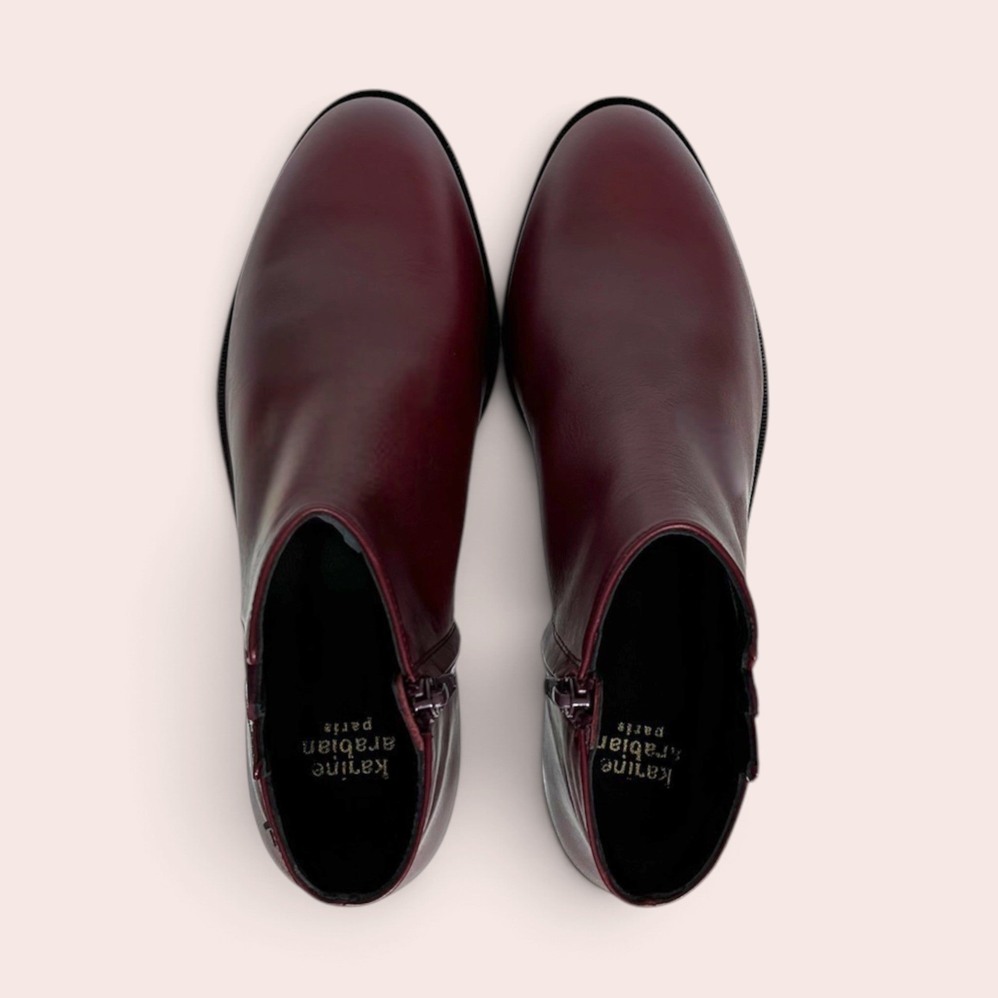 Bottines plates pour femme en cuir bordeaux avec fermeture éclair latérale, vue de dessus sur fond clair