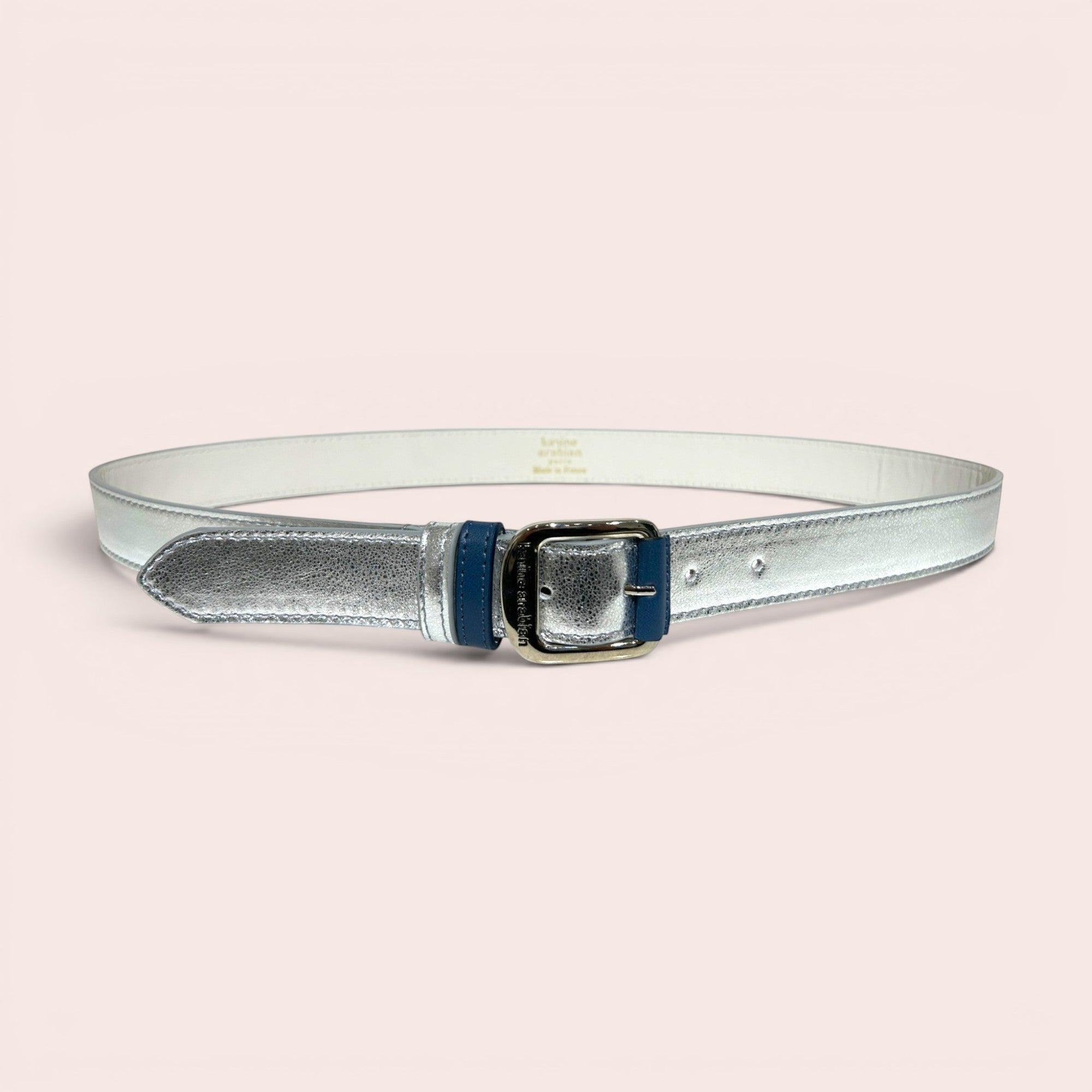 Ceinture fine en cuir argenté métallisé texturé avec boucle carrée argentée et passant bleu marine. Idéale pour accessoiriser une robe ou un jean.