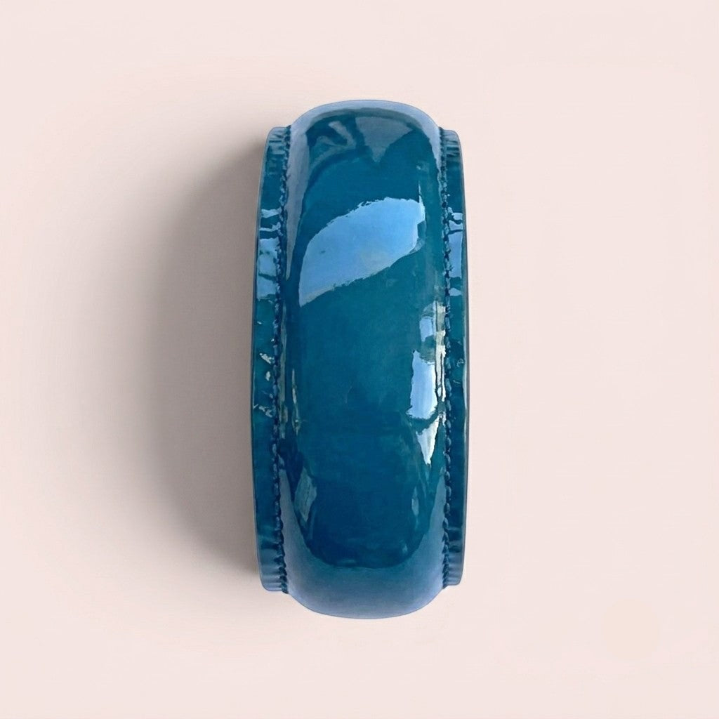 Wide bangle bracelet in glossy duck blue patent leather with stitched edges, viewed from the side.