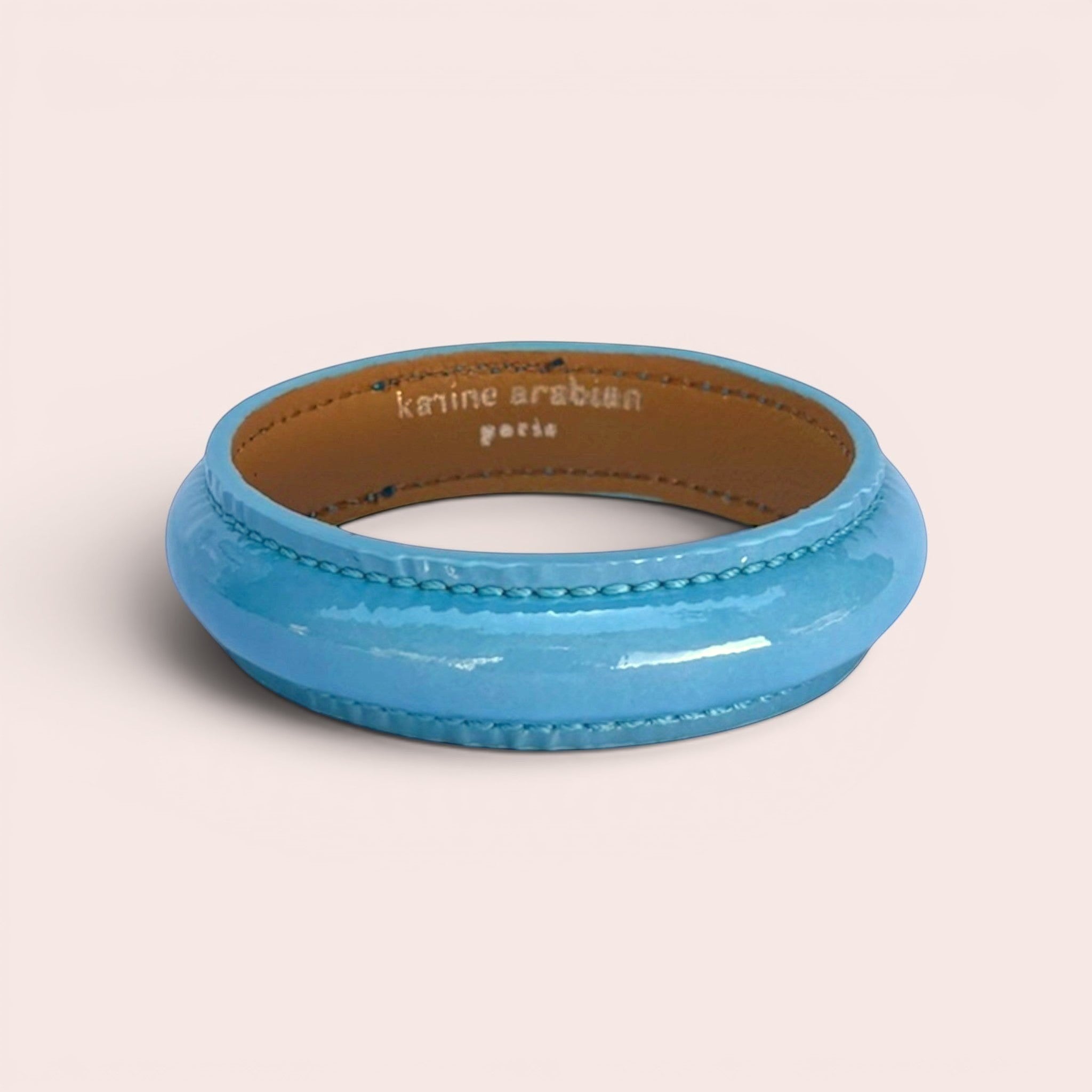 Maya blue patent leather bangle bracelet with visible stitching and tan leather interior lining