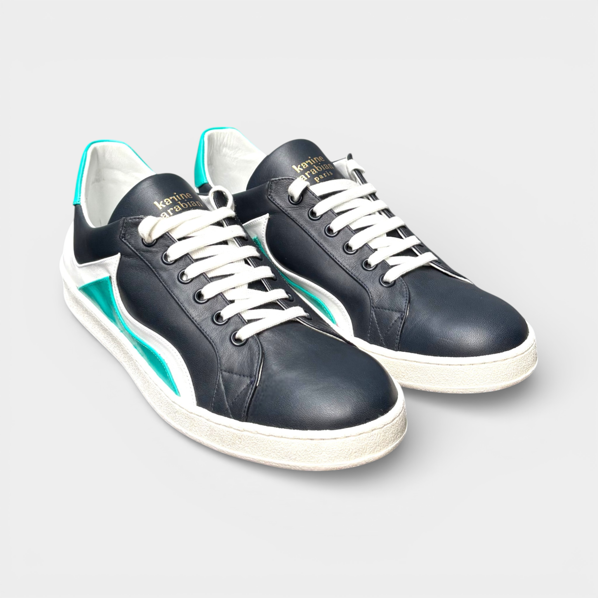 Dark navy leather men's sneakers with white laces, white sole, and teal accents on the heel and side stripe.