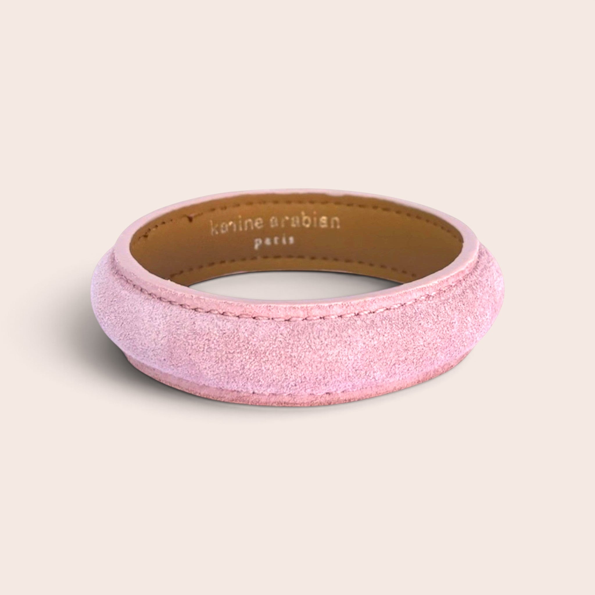 Pale pink suede leather bangle bracelet with Karine Arabian Paris branding on the inner lining
