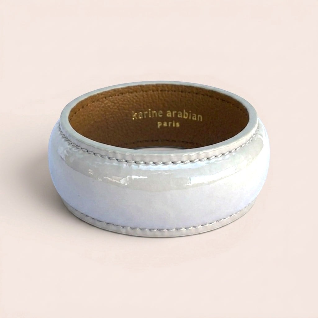 Wide pearl grey patent leather bangle bracelet with snake print texture and gold embossed Karine Arabian logo interior.