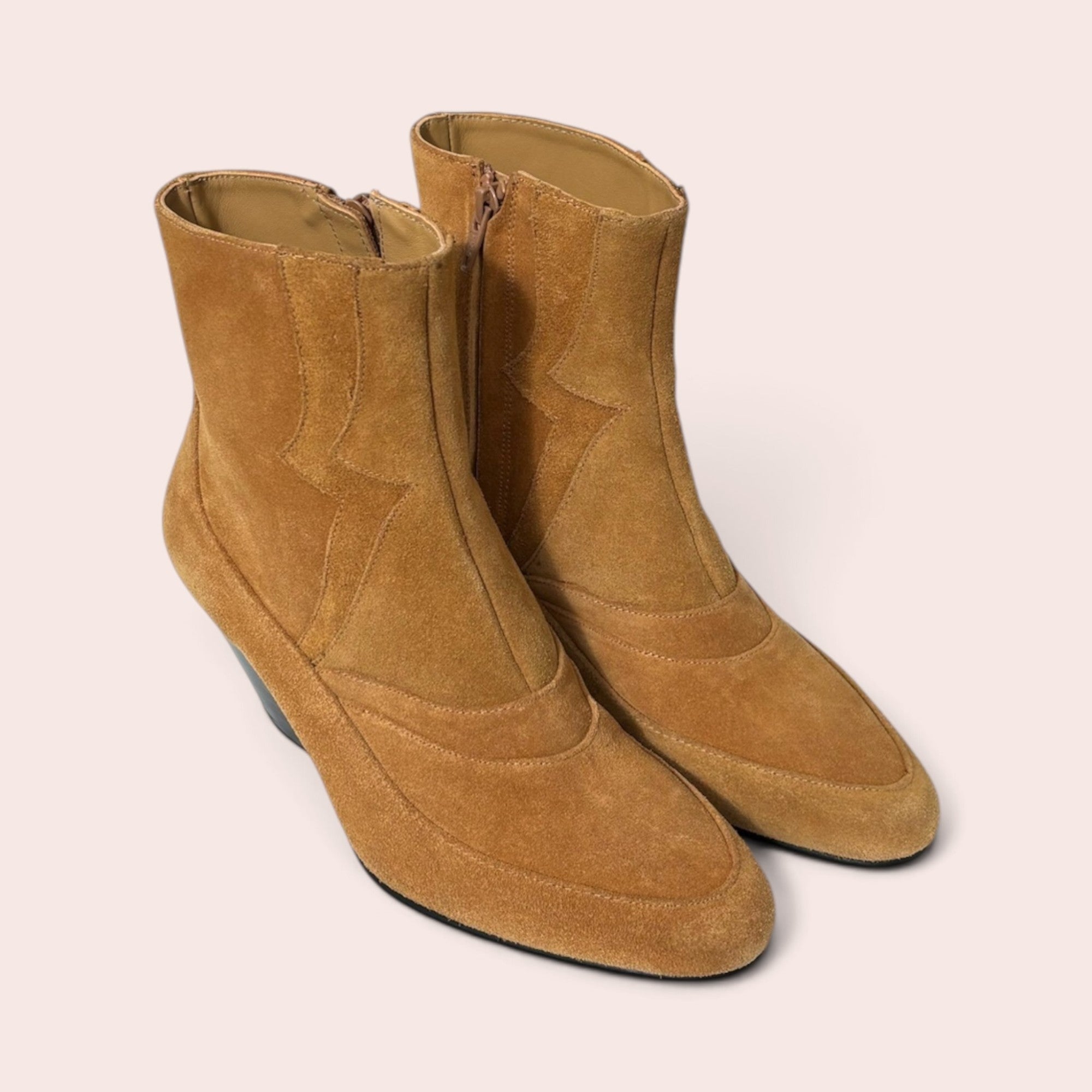 Pair of tan suede western-style ankle boots with pointed toes, decorative stitching, and a unique sculptural heel.