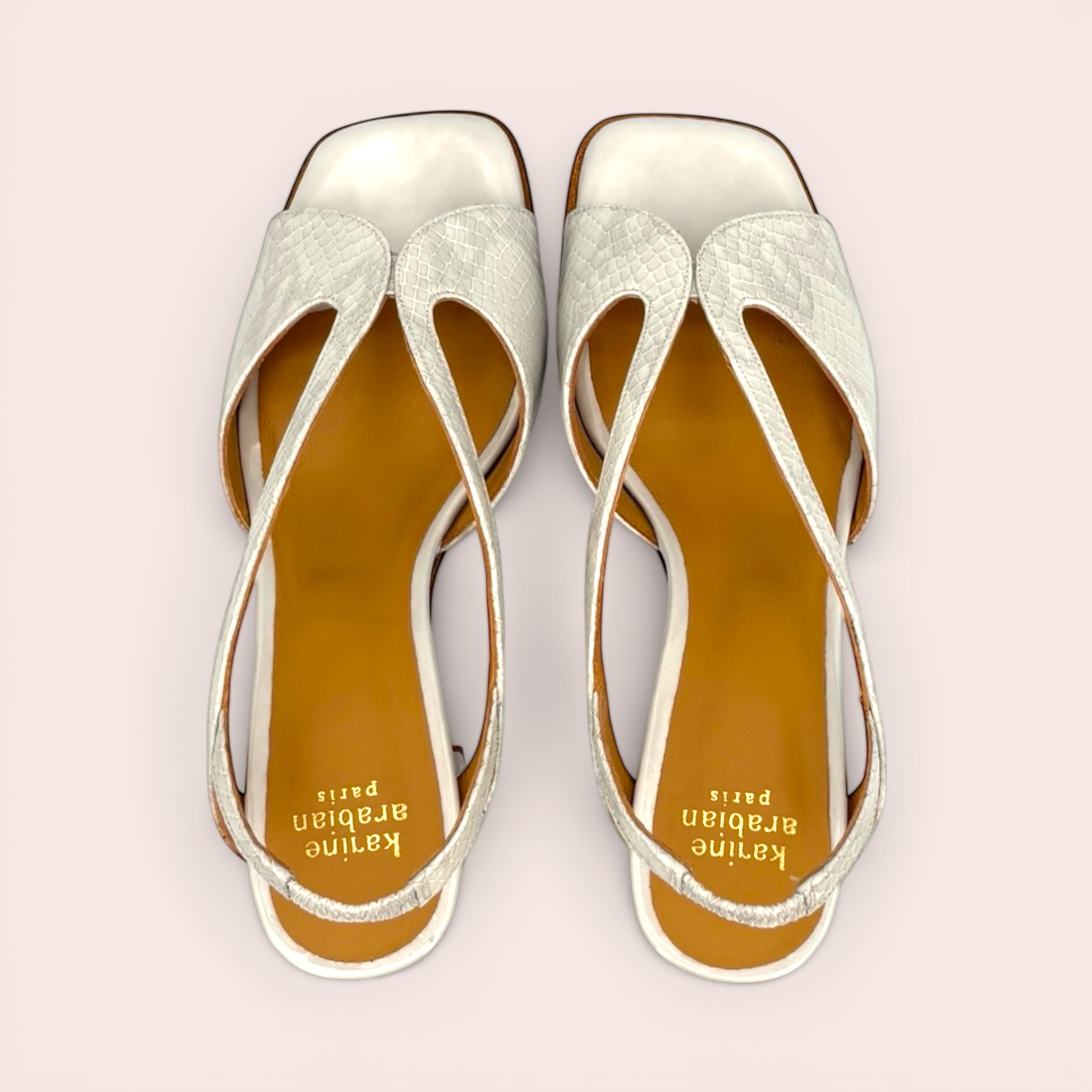 White leather sandals with a subtle snakeskin texture and a unique cut-out design, featuring a slingback strap and square toe.